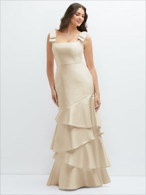 Champagne satin maxi dress with bow shoulders and asymmetrical tiered ruffle skirt