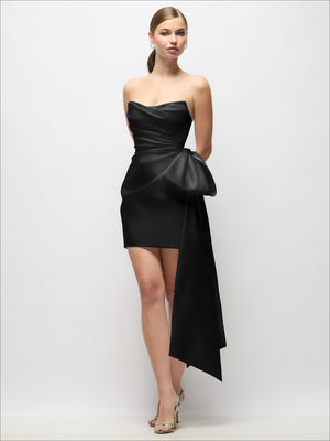 Black strapless pleated satin mini dress with dramatic draped bow tail and covered buttons