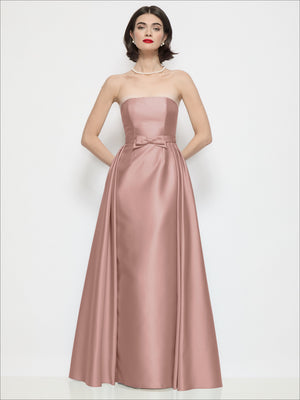 Blush pink satin strapless column dress with bow at waist and overskirt overlay