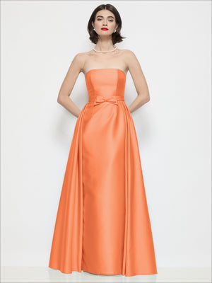 Orange strapless satin column dress with bow waist and draped overskirt