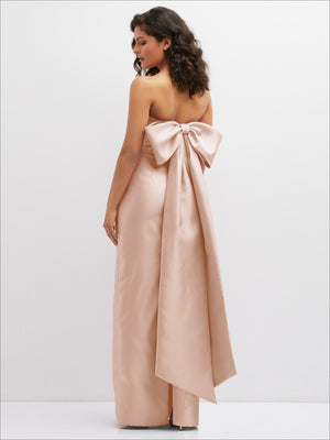Strapless draped column dress in blush pink with oversized bow detail at back