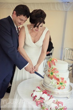 bride and groom cutting floral wedding cake bride and groom cutting floral wedding cake