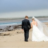 bride and groom walking along beach in Ireland
