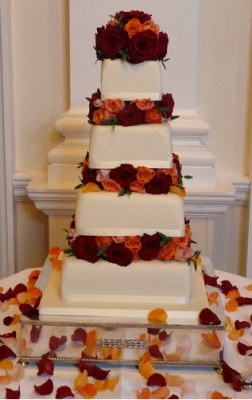 tiered wedding cake decorated with red and orange roses 