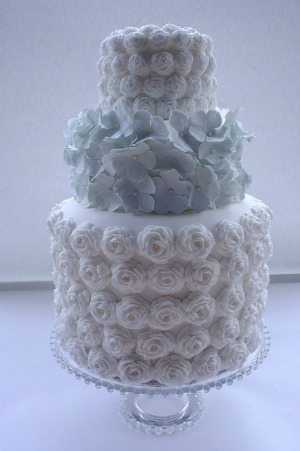 tiered wedding cake with roses and blue hydrangeas