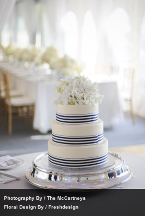 white tiered wedding cake with navy stripe ribbons 