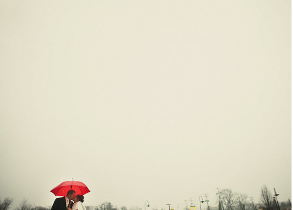 bride and groom at January wedding with red umbrella
