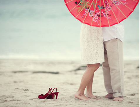 Couple holding red parasol for engagement photo shoot 