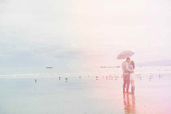 man and woman with umbrella on beach