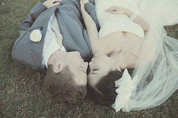 bride and groom laying on grass