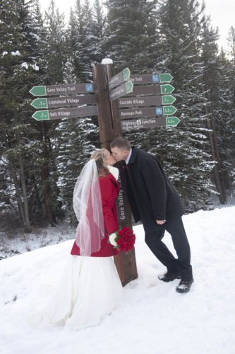 bride in red coat with red rose bouquet in snow
