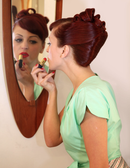 woman putting on lipstick in mirror
