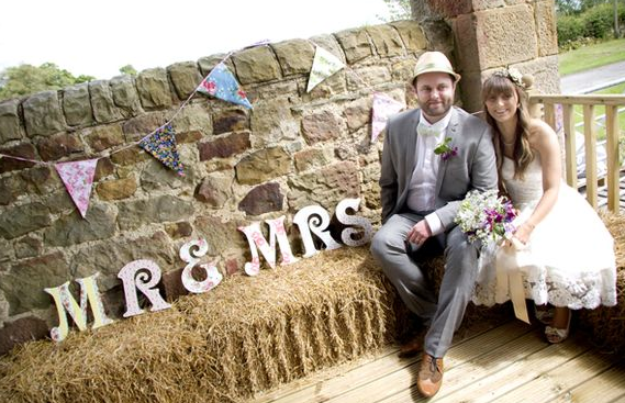 bride and groom on haybale at barn wedding