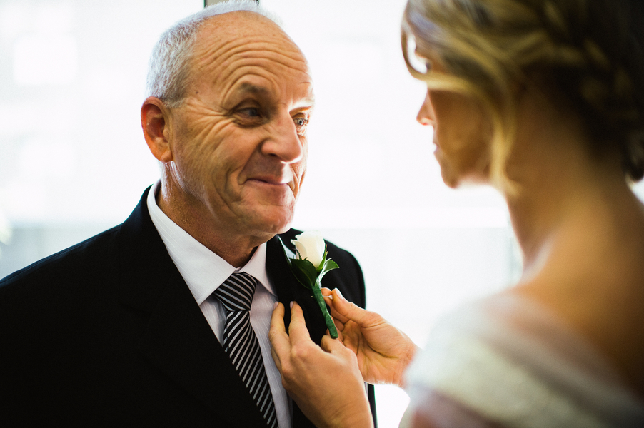 Bride putting buttonhole on father's lapel 